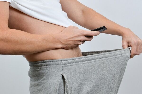 رجل ينظر إلى قضيبه المتضخم من خلال سرواله